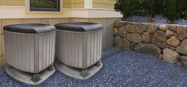 Two large residential cooling units outside of a house