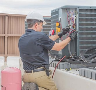 An air conditioning technician is inspecting a cooling unit